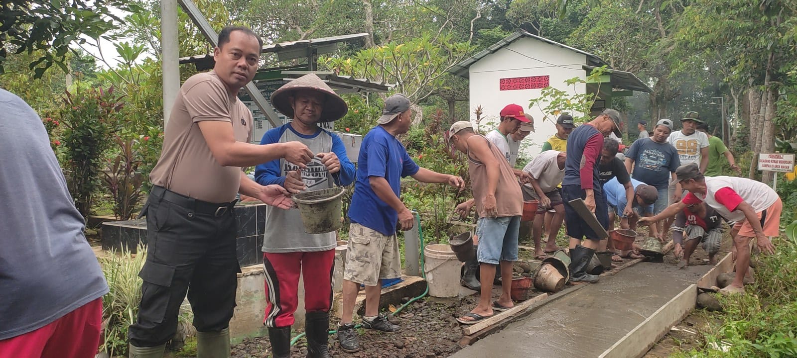 Bhabinkamtibmas Polsek Patikraja Polresta Banyumas Ikuti Kerja Bakti Pengecoran Jalan Makam Desa Sidabowa